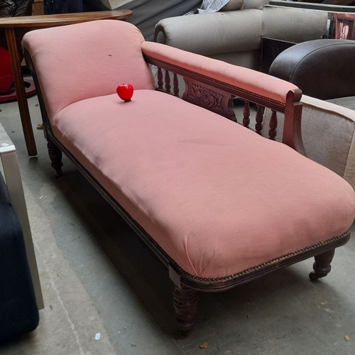 970 - A Victorian chaise longue featuring turned wood legs and ornate carved detailing, upholstered in pin... 