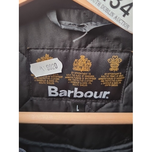 434 - A black quilted Barbour jacket with zip and button closure, size L. In good order.