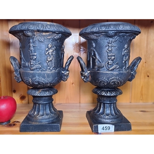 459 - A pair of mini Victorian-style heavy cast iron urns with detailed classical reliefs. Features ornate... 