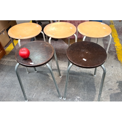 490 - A set of five mid-century modern stacking stools, featuring metal legs and circular wooden seats in ... 