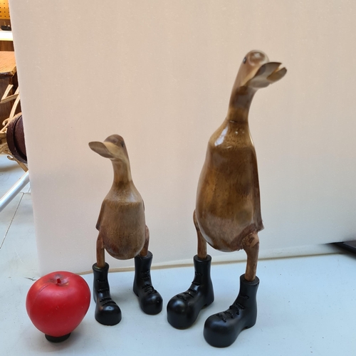 401 - A characterful hand carved  wooden Duck along with duckling wearing cast metal heavy boots.