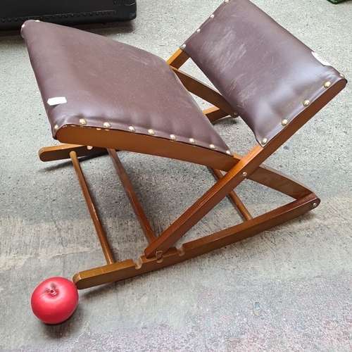 495 - A folding wooden kneeling stool with brown vinyl upholstery and brass rivets.