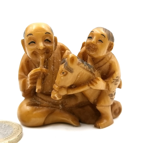 517 - An unusual Japanese original antique bone carved Netsuke (two holes) depicting two figures - one rid... 