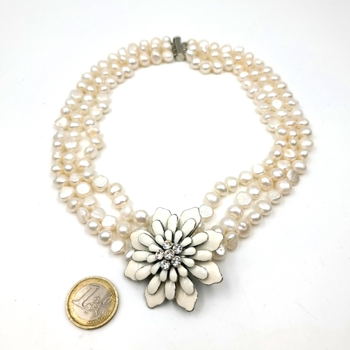 529 - A three strand freshwater pearl necklace set with a porcelain mounted floral pendant with gem settin... 