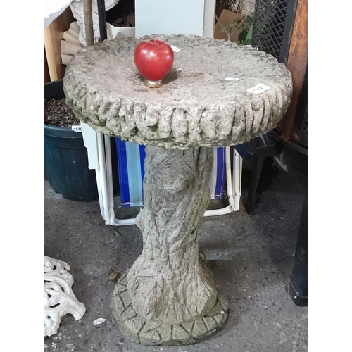 1023 - A large reconstituted stone birth in the form of a tree stump. 77cm tall 43cm wide.