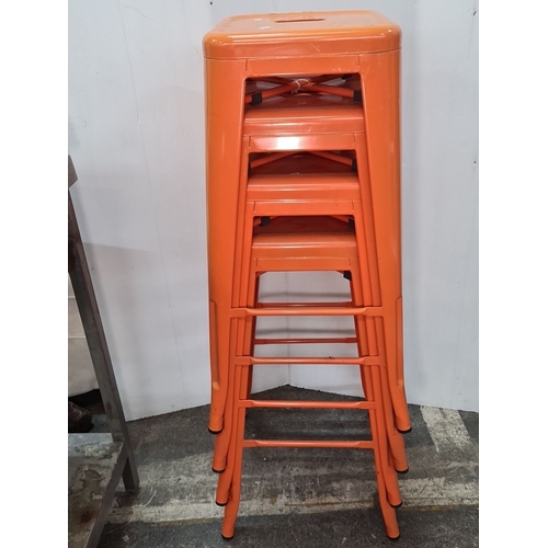 750 - Set of four industrial sturdy metal bar stools with a bright orange finish, featuring a stackable de... 