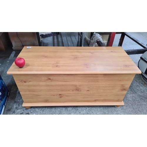 782 - Wooden storage chest with hinged lid. Features a light oak veneer finish. Measures approximately [in... 