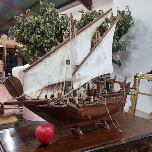 811 - A large vintage handcrafted wooden model ship with intricate detailing and cloth sails. Notable wood... 