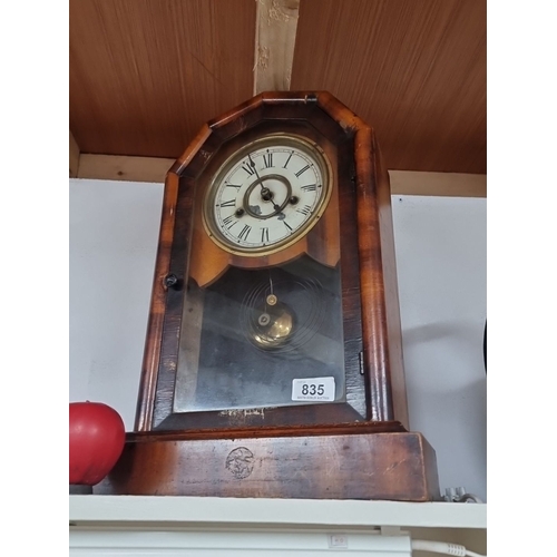 835 - Antique eight day wooden mantel clock with a brass pendulum and Roman numeral dial. It exhibits Vict... 