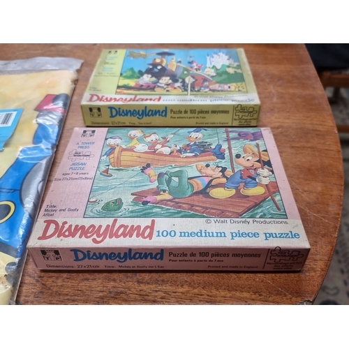 862 - The lot includes two 100-piece Disneyland puzzles by Tower Press, specifically the Mickey Mouse Trai... 