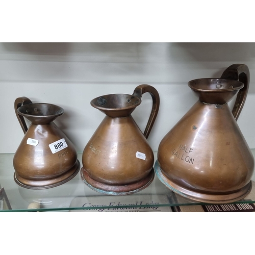 880 - A set of three vintage copper measuring jugs labeled Pint, Quart, and Half Gallon featuring a maker'... 