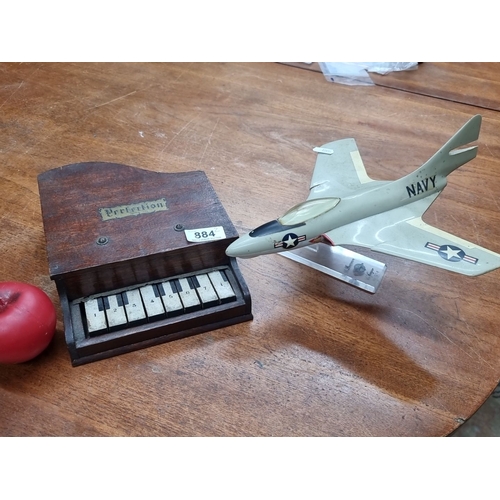 884 - Two items including a Vintage mini piano made of oak and an F9F-8 Cougar Grumman Navy jet model on a... 