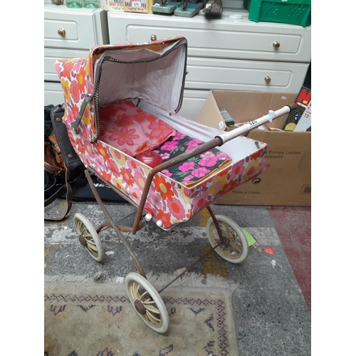 926 - A rather charming vintage child's doll pram decorated in a vibrant floral pattern. The Following Lot... 