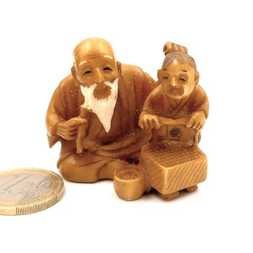 512 - An antique original Japanese  carved Netsuke figure (two holes) depicting an elderly seated man with... 