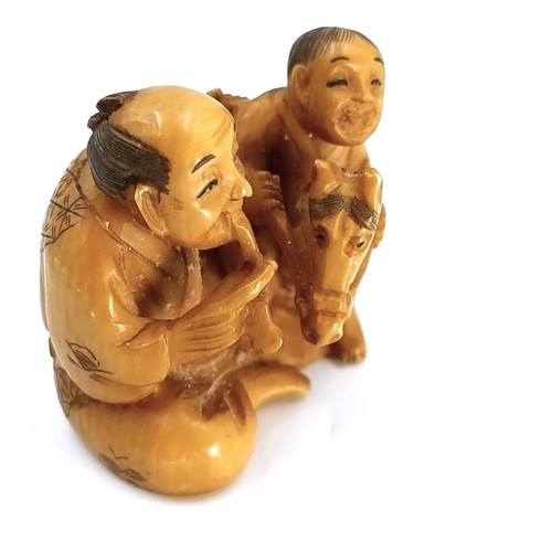 517 - An unusual Japanese original antique bone carved Netsuke (two holes) depicting two figures - one rid... 