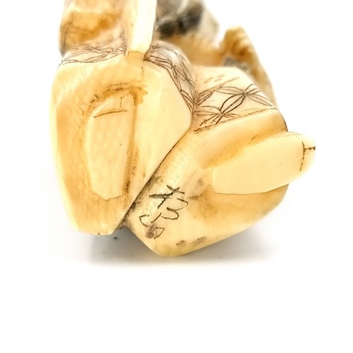 1063 - An antique carved bone Japanese netsuke with two holes for a toggle attachment with artist signature... 