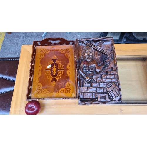 414 - Pair of wooden trays: one with detailed floral inlay, the other featuring a carved human figure in r... 