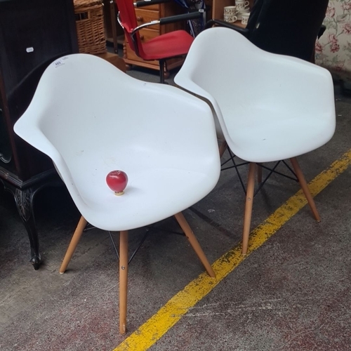 460 - Pair of contemporary white molded plastic armchairs with wooden legs and black metal supports.