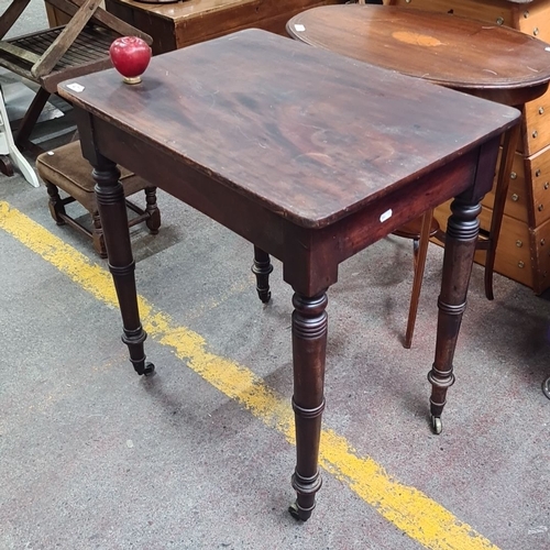 471 - Mid-19th Century Victorian side table in mahogany, featuring turned legs on casters.