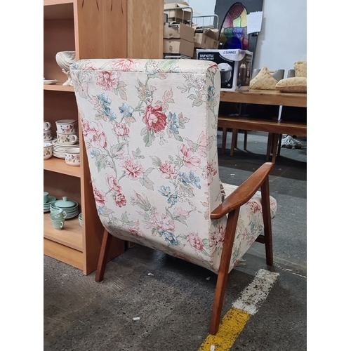 482 - Mid-Century Modern armchair with floral upholstery and wooden armrests. Features a high back and mat... 