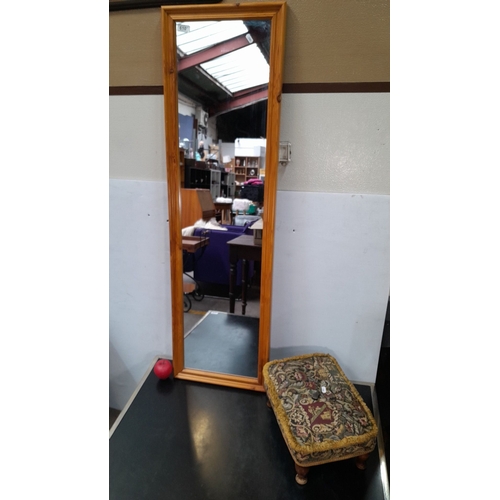 610 - Full-length wall mirror with a wooden frame, accompanied by a tapestry-covered footstool.