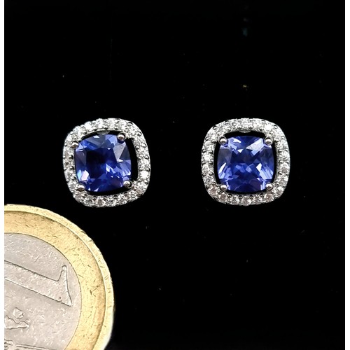 566 - A fine pair of blue sapphire stud earrings with white sapphire surround mounted in sterling silver. ... 