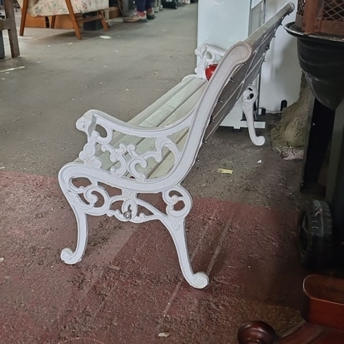 701 - A neat site possibly Childs White wooden bench with ornate cast iron sides, featuring a classic slat... 