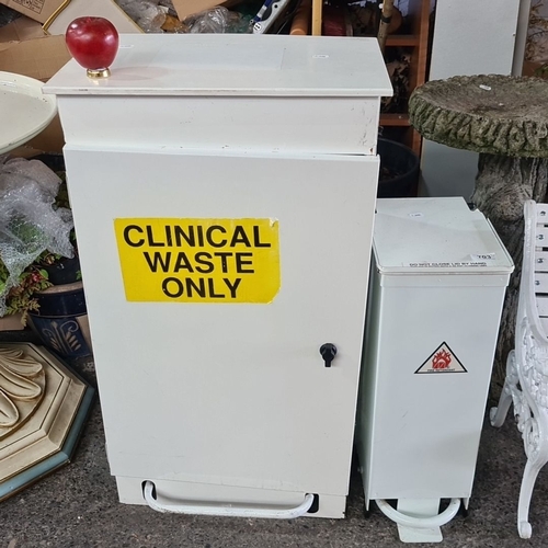 703 - Includes two white metal waste  bins with pedal-operated lids, one labeled 