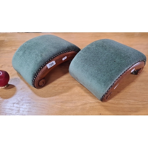 709 - Pair of upholstered footstools with dark green fabric and decorative wooden trim.