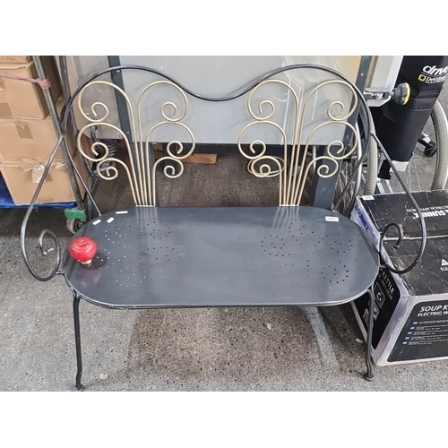 711 - Wrought iron bench with ornate scrollwork backrest and perforated seat. Distinctive red finial armre... 