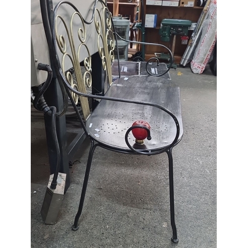 711 - Wrought iron bench with ornate scrollwork backrest and perforated seat. Distinctive red finial armre... 