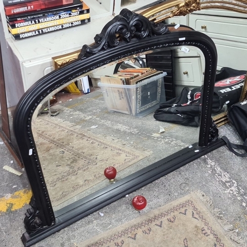 716 - Antique black-framed over mantle mirror with ornate crest detailing. Wooden backing visible.