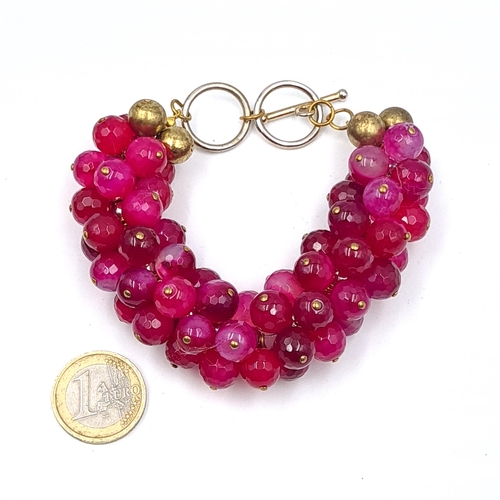 575 - A cranberry coloured designer multi strand bracelet with T bar clasp. Weight 104.08 grams. Boxed.