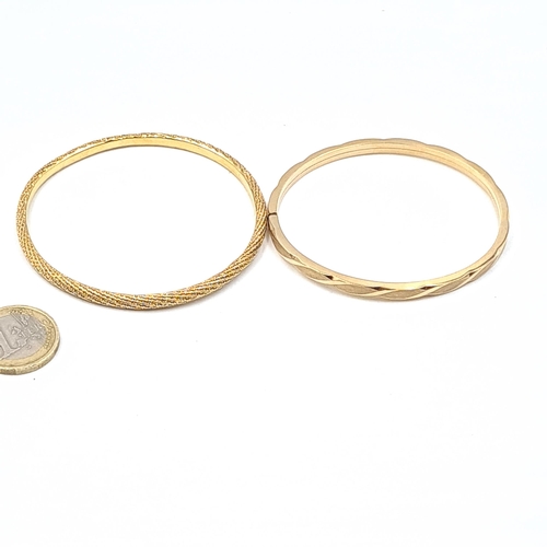 577 - Two gold plated bangles include a twist example. Total weight of 24.07 grams. Boxed.