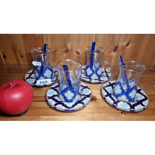 669 - Set of four ornate glass tea cups with matching saucers, featuring intricate blue and white patterns... 