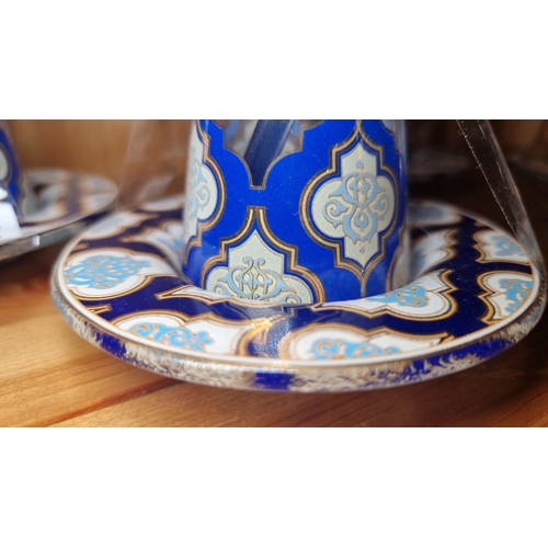 669 - Set of four ornate glass tea cups with matching saucers, featuring intricate blue and white patterns... 