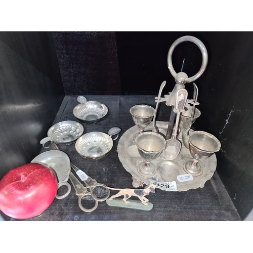 429 - A mixed lot of silver-plated items. The lot includes an ornate egg coddler set with spoons, decorati... 