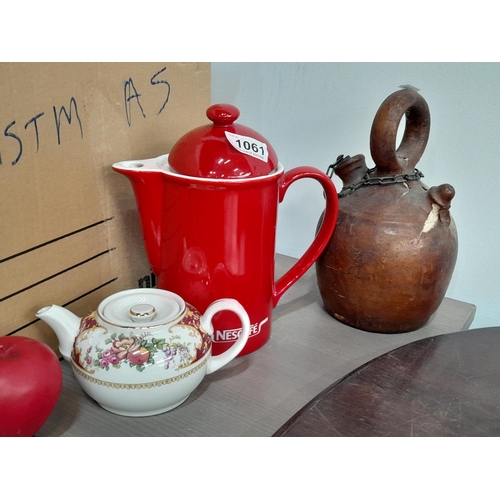 1061 - A selection of three items including a red ceramic Nescafe coffee, a vintage leather encased flask w... 