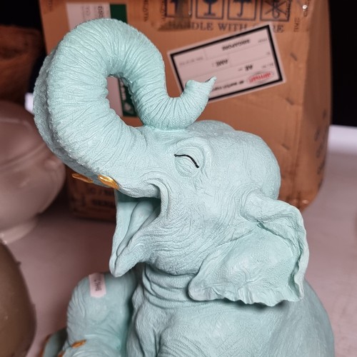 391 - A characterful figure of a cheerful baby elephant in a turquoise shade with gold toned nails and tus... 