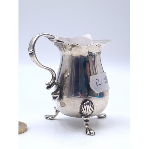 26 - A very nice example of a small cream jug with pretty sea handle with scalloped rim standing on three... 