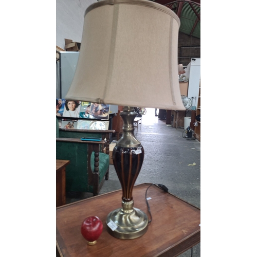 749 - A handsome table lamp with a brass base and a striped brown glass body. It is topped with a beige fa... 