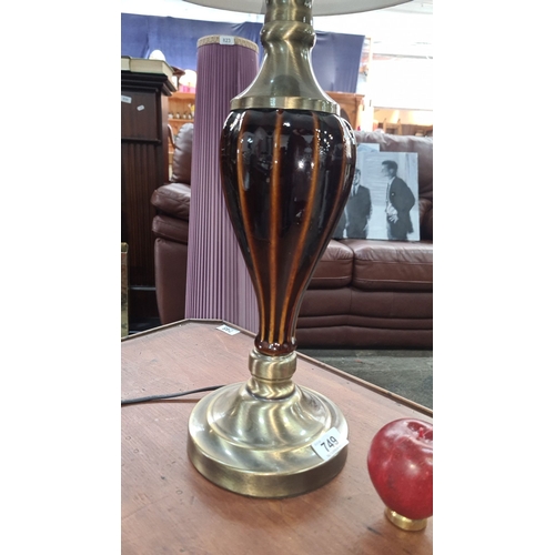 749 - A handsome table lamp with a brass base and a striped brown glass body. It is topped with a beige fa... 