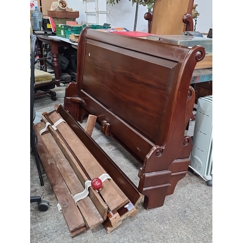 753 - Star Lot: A Victorian style mahogany sleigh bed frame, featuring intricate scroll details on the hea... 