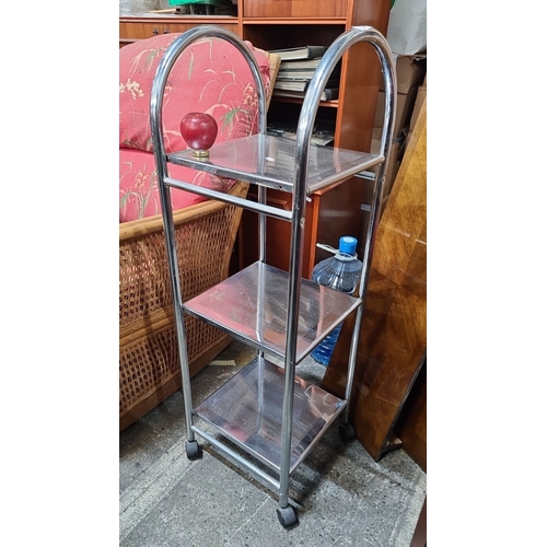 766 - A Chrome-plated metal utility cart with three perforated shelves and four caster wheels for easy mob... 