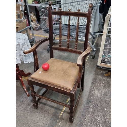 814 - An early 20th Century oak armchair featuring turned spindles and a leather upholstered seat.