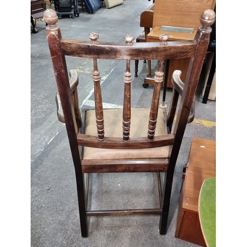 814 - An early 20th Century oak armchair featuring turned spindles and a leather upholstered seat.