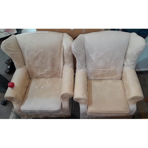 960 - A pair of high wingback armchairs, covered in a slip on damask cream pattern. Originally purchased f... 