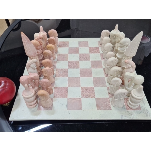 770 - A Hand-carved chess set made from stone. Includes intricately detailed pieces in shades of pink and ... 