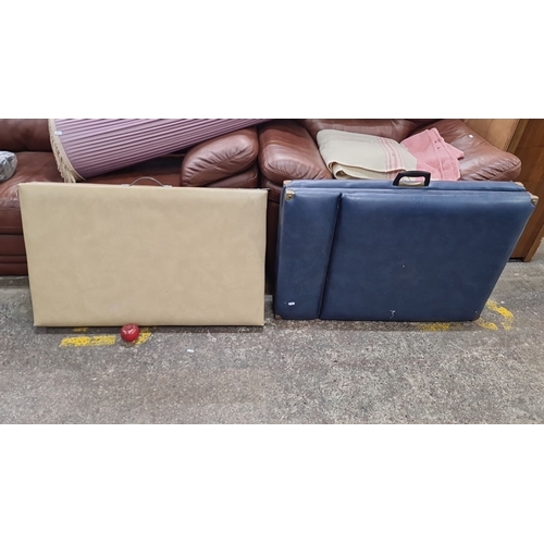 771 - Two Good folding massage tables. Features Beige and navy blue vinyl upholstery with wooden legs. The... 