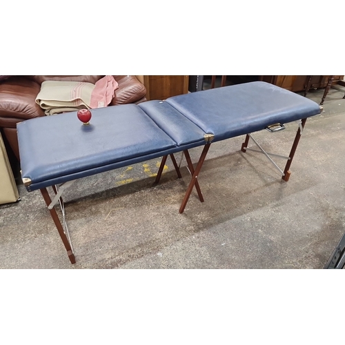 771 - Two Good folding massage tables. Features Beige and navy blue vinyl upholstery with wooden legs. The... 